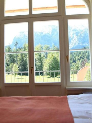 Zimmer mit großen Fenstern und beeindruckendem Alpenblick im Hotel Schloss Elmau.
