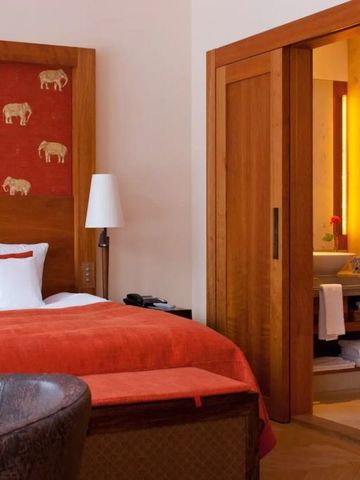 Elegantes Hotelzimmer mit roter Bettwäsche und angrenzendem Badezimmer