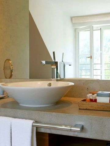 Modernes Badezimmer mit großer Waschschale und Balkonblick in Schloss Elmau.