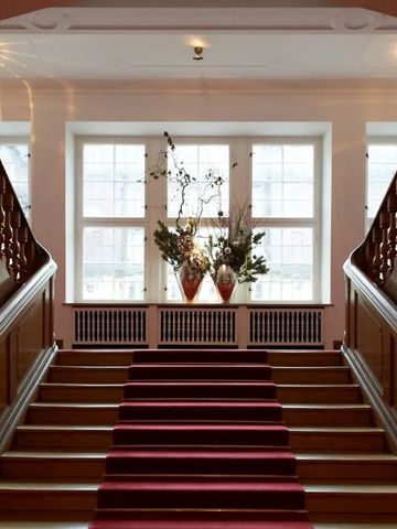 Prächtige Treppe mit rotem Teppich und eleganter Dekoration im Schloss Elmau.