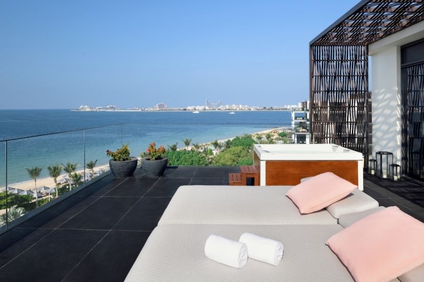 Private Dachterrasse im Banyan Tree Dubai mit gemütlichen Liegen, Whirlpool, stilvollem Design und weitem Blick über das Meer und die Skyline von Dubai, inklusive Palmenstrand im Vordergrund.