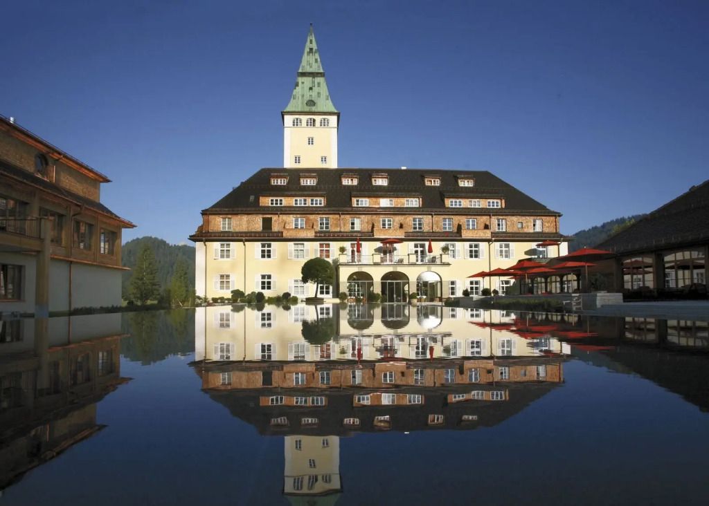 Historische Schlossfassade von Hotel Schloss Elmau spiegelt sich im Wasserbecken.